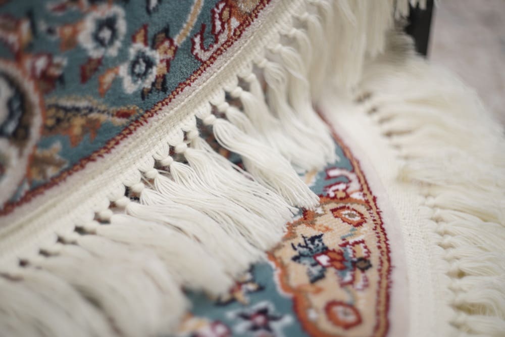 Close-up of a colorful patterned rug with intricate designs and white fringed edges, adding a touch of artistry to any space—similar to the detailed care found in alterations and tailoring Baldwinsville.