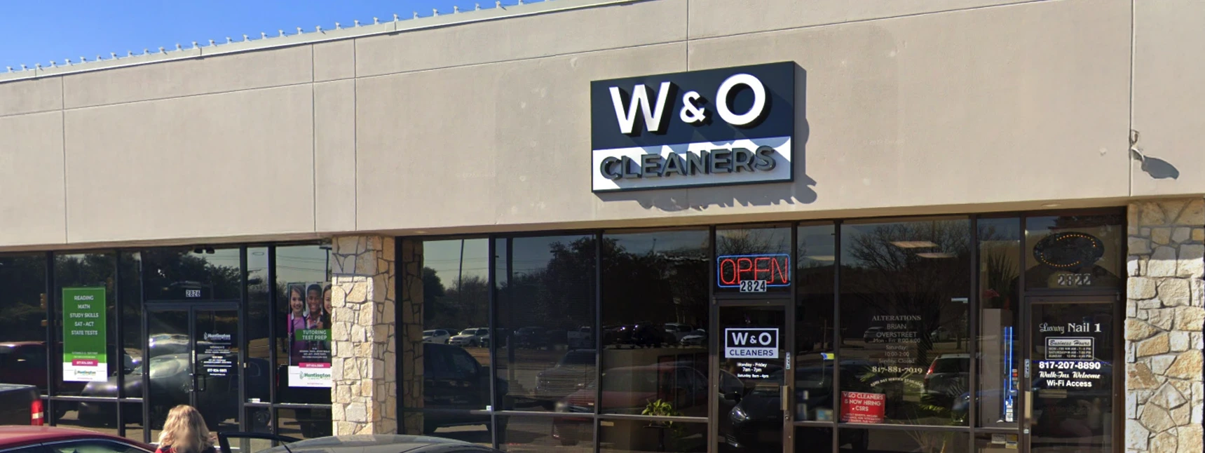 Storefront of W&O Cleaners in a strip mall, with a prominent sign above the entrance and 